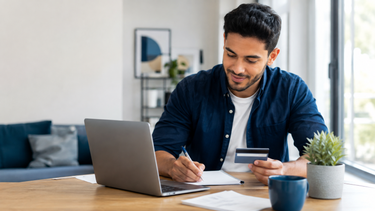 Young adult reviewing a budget and credit card at home